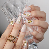 Thumbnail for Close-up of hands with beige nail polish and gold accents holding a clear glass.