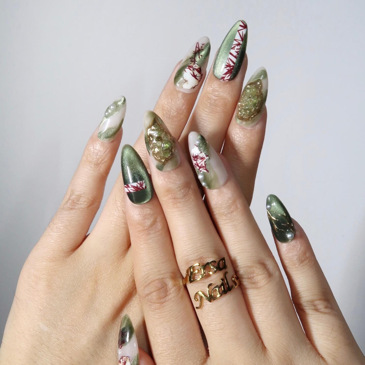 Hand with green and gold nail art on a plain background