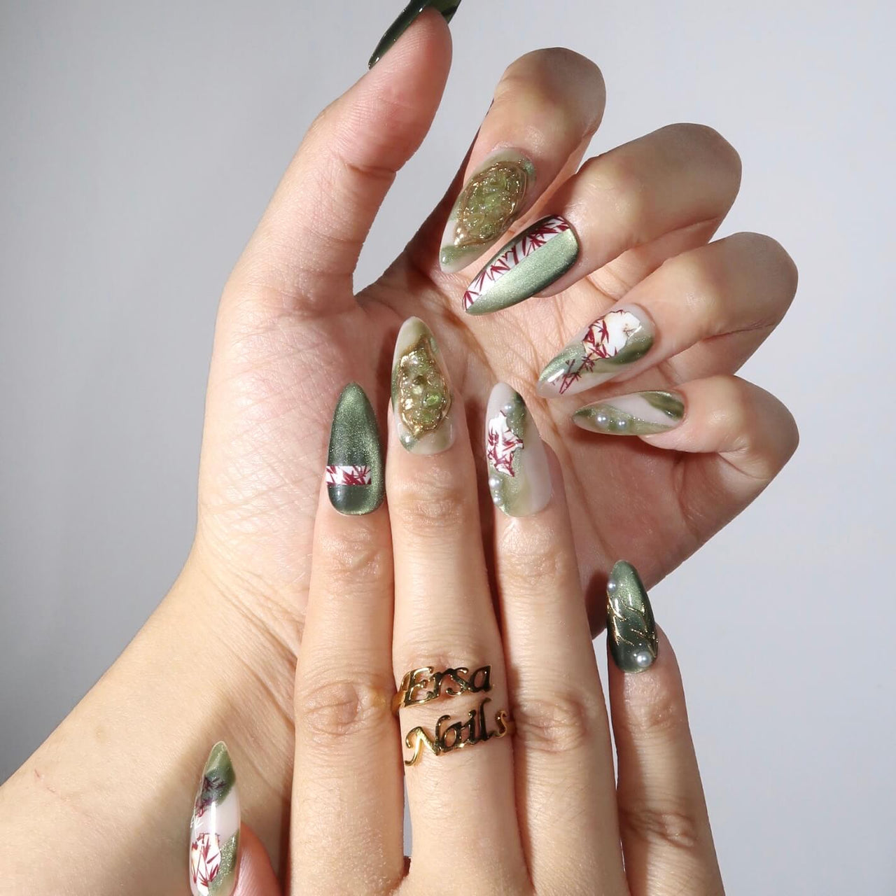 Hand with green and red floral nail art on a neutral background